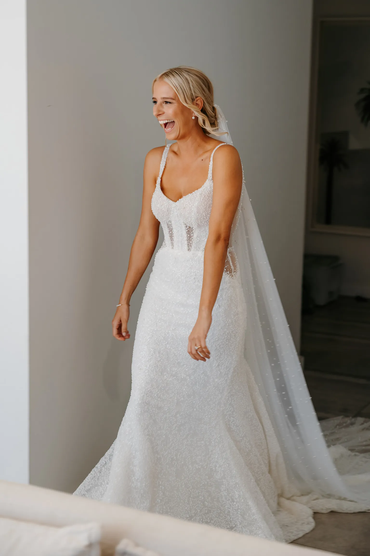 Laughing bride in a beaded wedding gown and cathedral veil, hair and makeup by Lisa Fowler